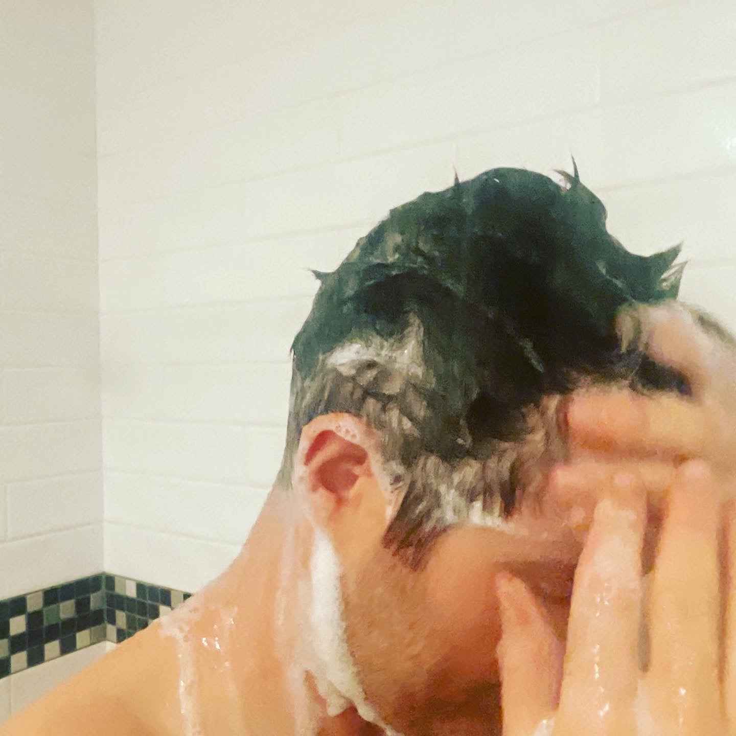 Shampoo foam on head during shower, hands applying cleanser