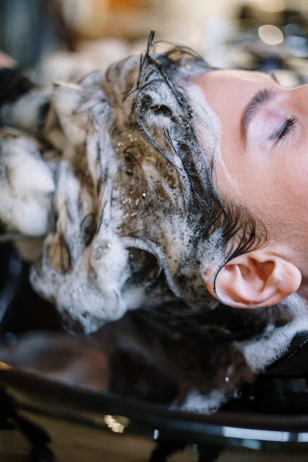 Shampoo lather on hair and face, person with wet, sudsy hair